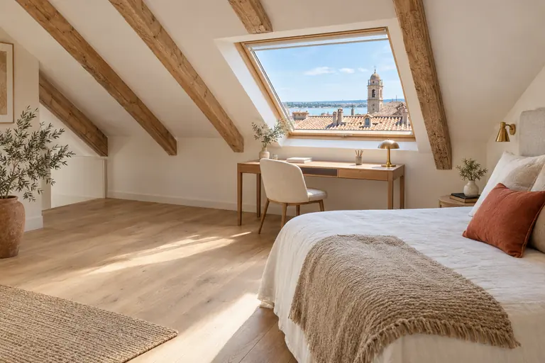 Pièce aménagée sous les toits d’une maison de ville avec chevrons apparents et fenêtre de toit donnant sur les toitures