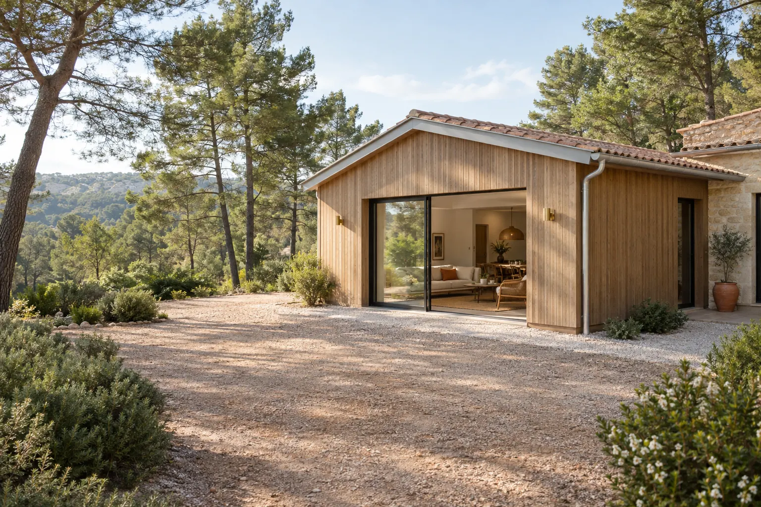 Extension bardée de bois en lisière de pinède, bande débroussaillée et gravillonnée autour des murs, gouttière dégagée des aiguilles de pin