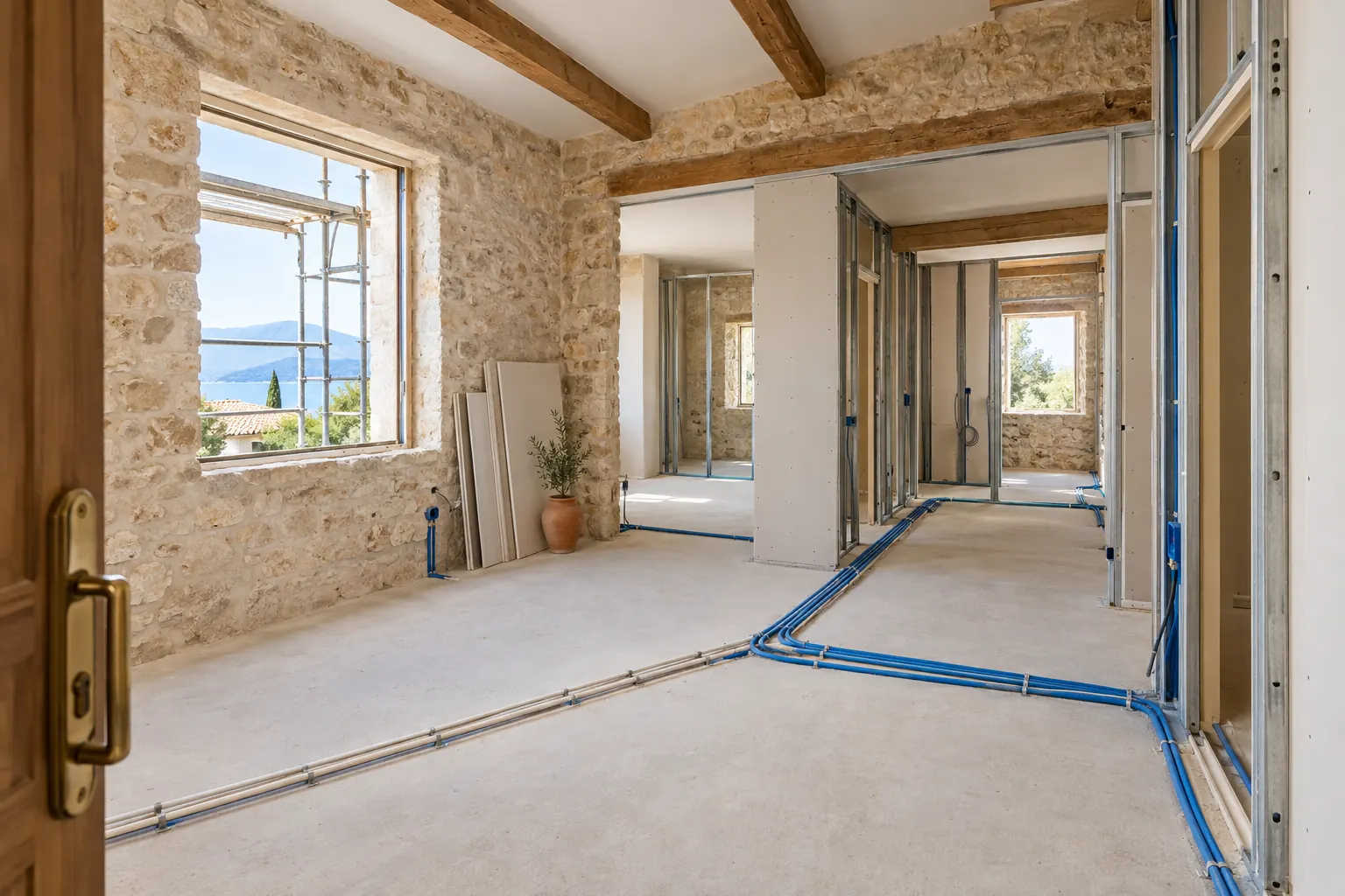 Rez-de-chaussée d’une maison en pleine rénovation avec cloisons sur rails, gaines électriques et tuyaux posés au sol